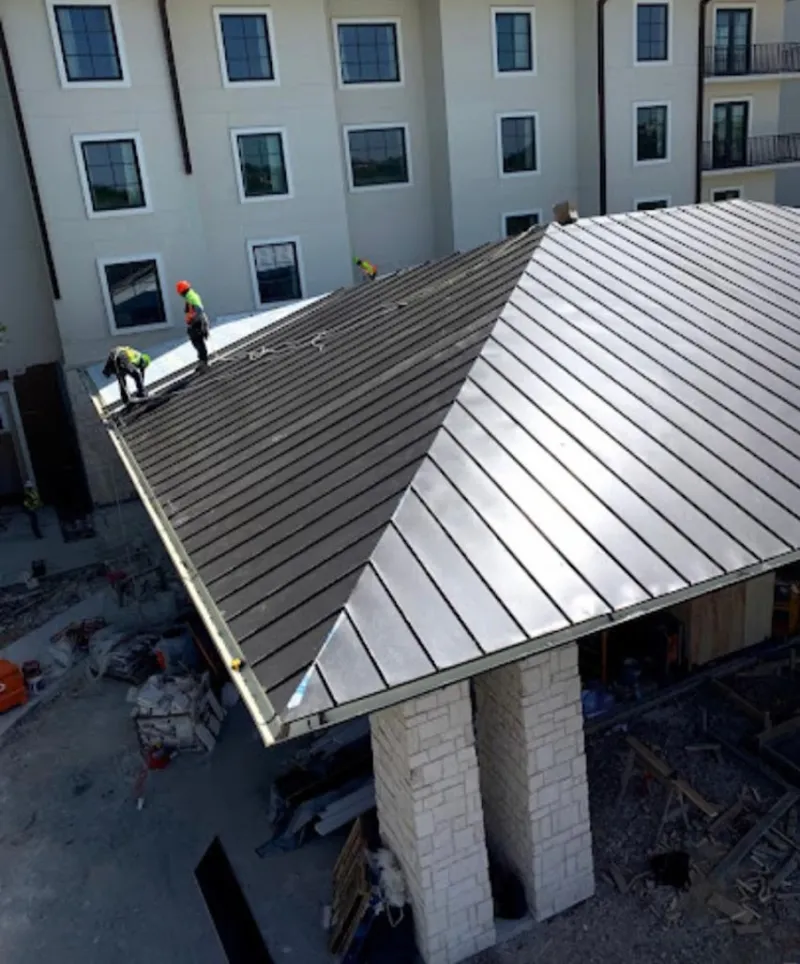Crew installing standing seam metal roof panels on a commercial project in Cottage Grove